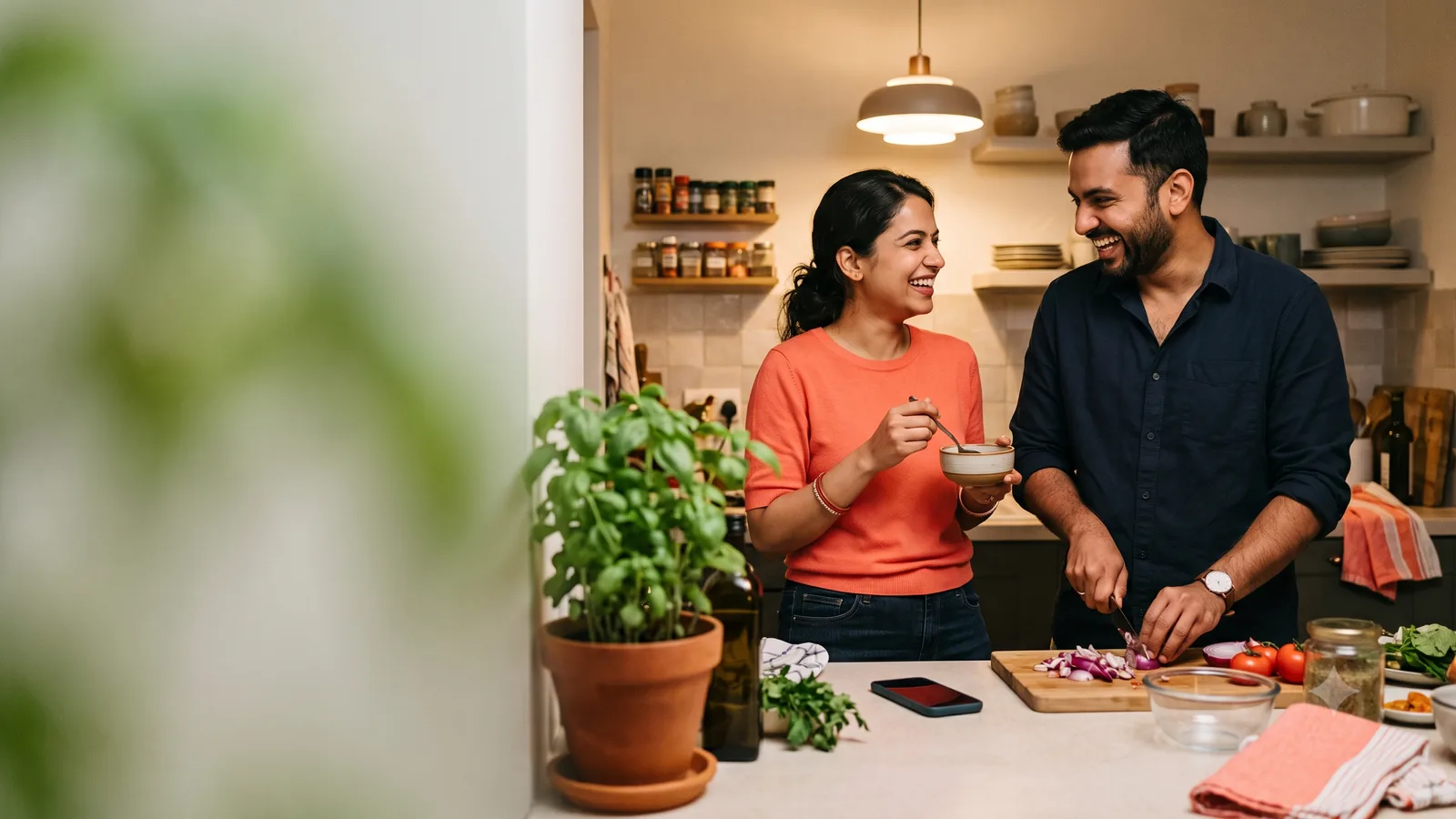 A DINK couple laughing together while cooking in their Mumbai kitchen.