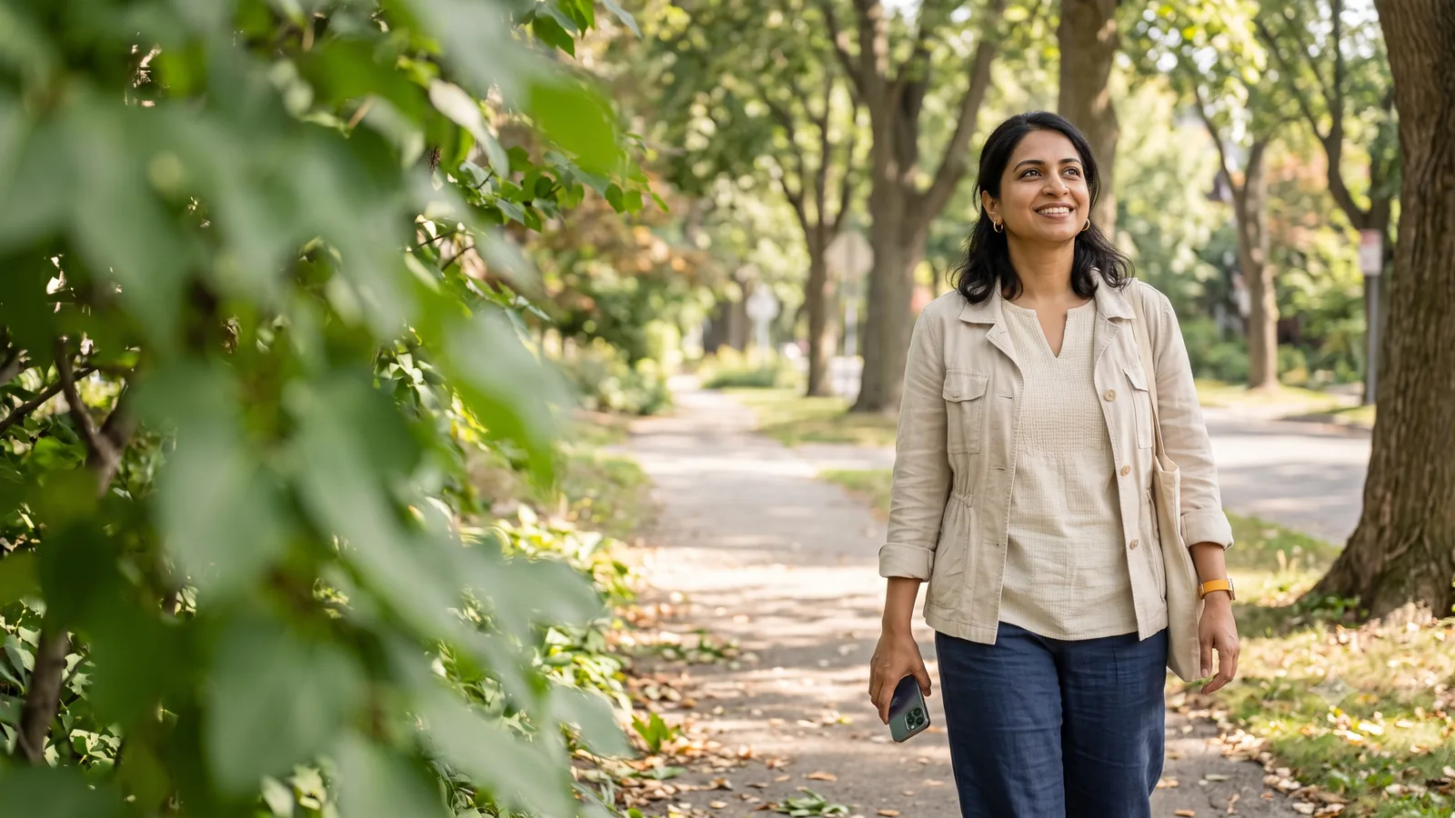 A woman walking through her neighborhood, checking her phone, at ease with where her money is growing.